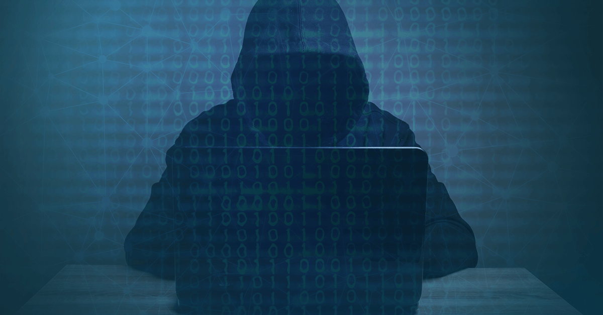 A hooded person sitting the dark on a laptop, shadows obscuring their face. Binary code overlayed across the image.