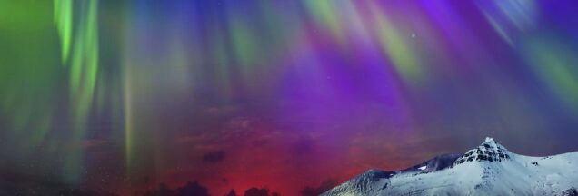 The northern lights over a snow-capped mountain.