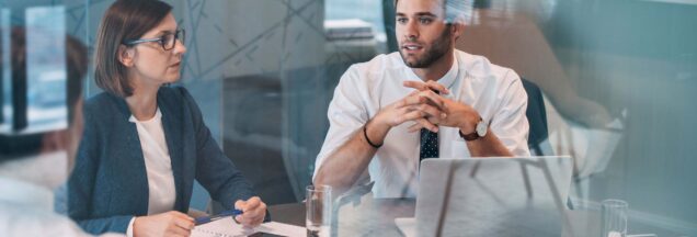 A man and woman sitting at a desk having a meeting.